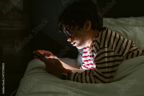 Boy looking at phone on bed photo