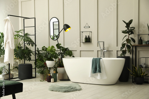 Stylish bathroom interior with modern tub and beautiful houseplants. Home design