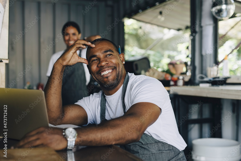 Smiling male owner with head in hand sitting food truck Smiling male owner with head in hand sitting food truck
