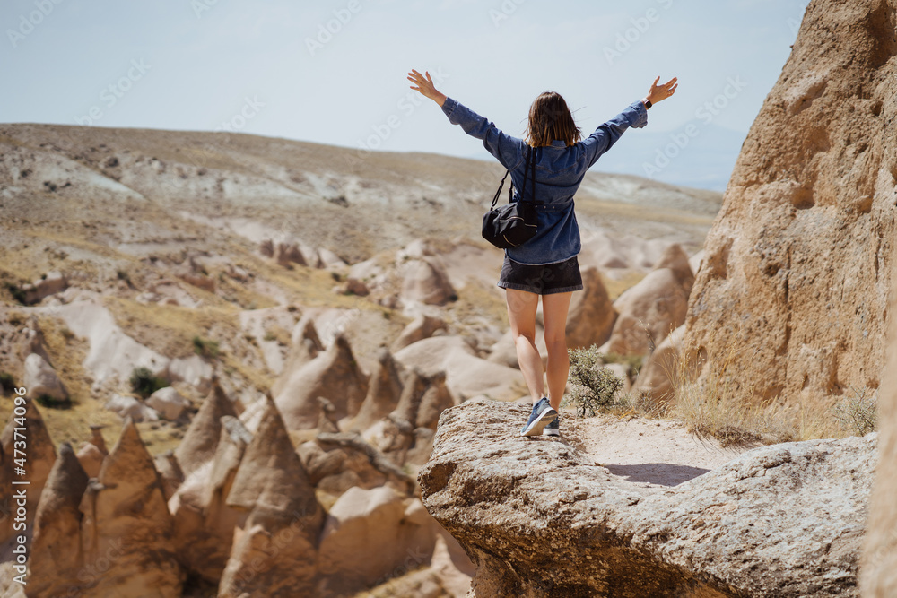 Young happy woman with backpack among mountains with raised hands enjoying the view Young happy woman with backpack among mountains with raised hands enjoying the view