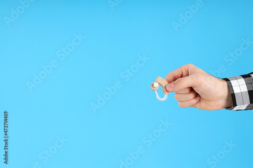 Male hand holds hearing aid on blue background