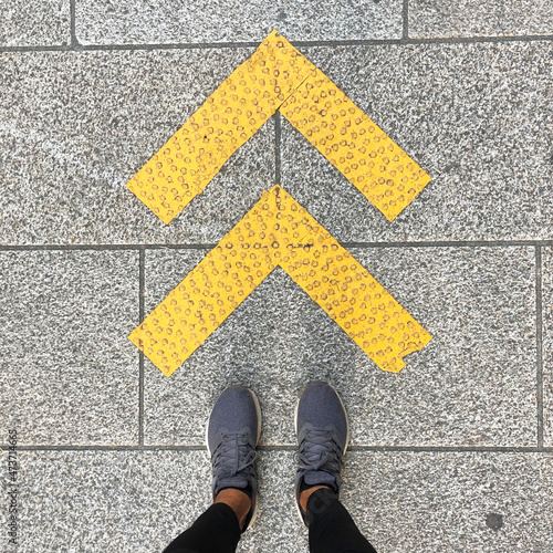 Feet standing by arrows on a sidewalk photo