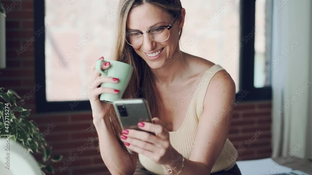 Video of beautiful business woman sending messages with her mobile phone while working with computer in the office at home. Video of beautiful business woman sending messages with her mobile phone while working with computer in the office at home.