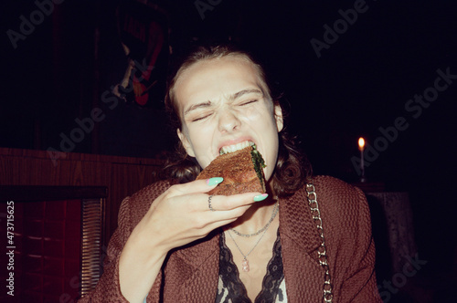 Hungry girl eating a spinach pie at night