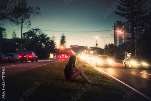 Woman sitting between busy roads