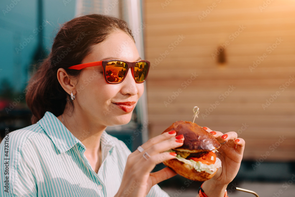 Happy asian young woman eating delicious fastfood burger in street food restaurant