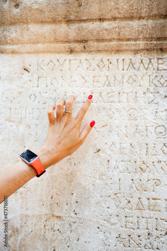 Woman philologist and tourist reads and tries to translate ancient Greek from columns in the ruins of an antique city. Linguistics and archaeology photo