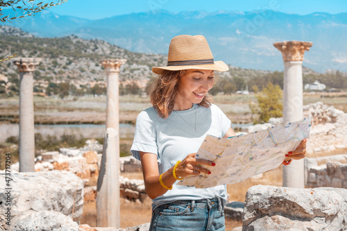 Traveler girl reading map at the ancient ruins of antique Greek city of Andriake in Turkey. Historical sightseeing and exploration concept