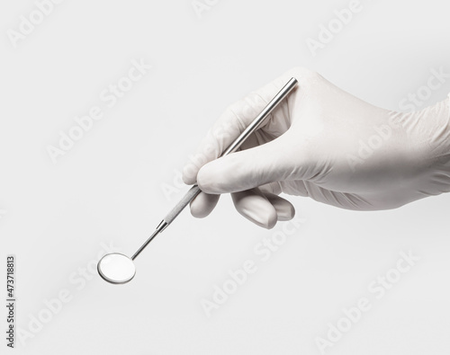 Dental mirror tool in dentist hand on white backgroud