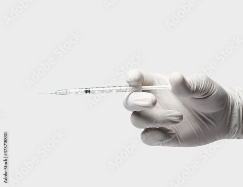 Hand in latex glove holding and prepare inject vaccine or insulin via syringe on white background