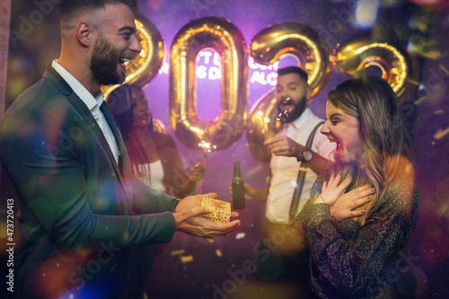 Happy beautiful couple celebrate New Year's Eve and exchanging gifts