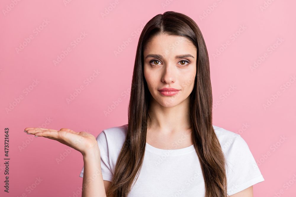 Portrait of attractive serious girl holding on palm offer copy empty space isolated over pink pastel color background Portrait of attractive serious girl holding on palm offer copy empty space isolated over pink pastel color background