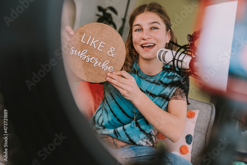 Girl showing like and subscribe sign while vlogging at home photo