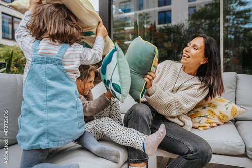 Mother and daughters doing cushion fighting at backyard photo