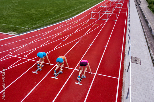 Germany, Baden Wurttemberg, Winterbach, Rear view of three female hurdlers right before start of race
