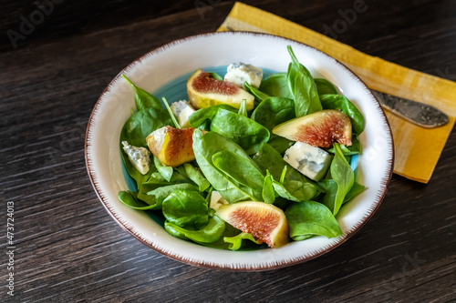 Fresh delicious salad with baby spinach, blue cheese and figs in vintage salad bowl, closeup
