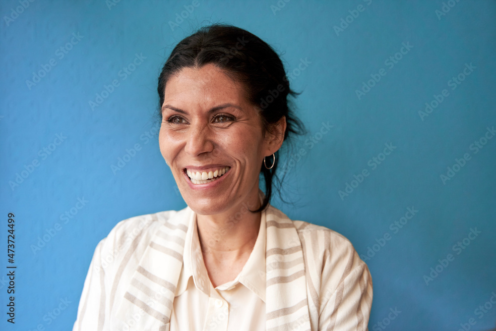 Laughing woman with brown eyes in front of blue wall Laughing woman with brown eyes in front of blue wall
