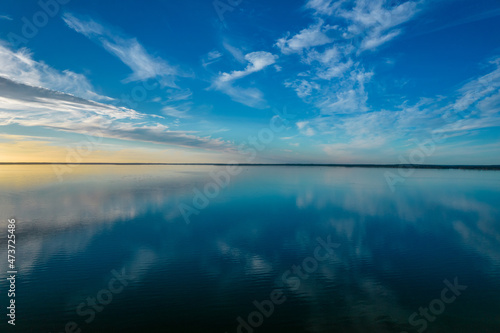 Beautiful landscape of the lake isunset. Blue sky, mirror image of white clouds in the water