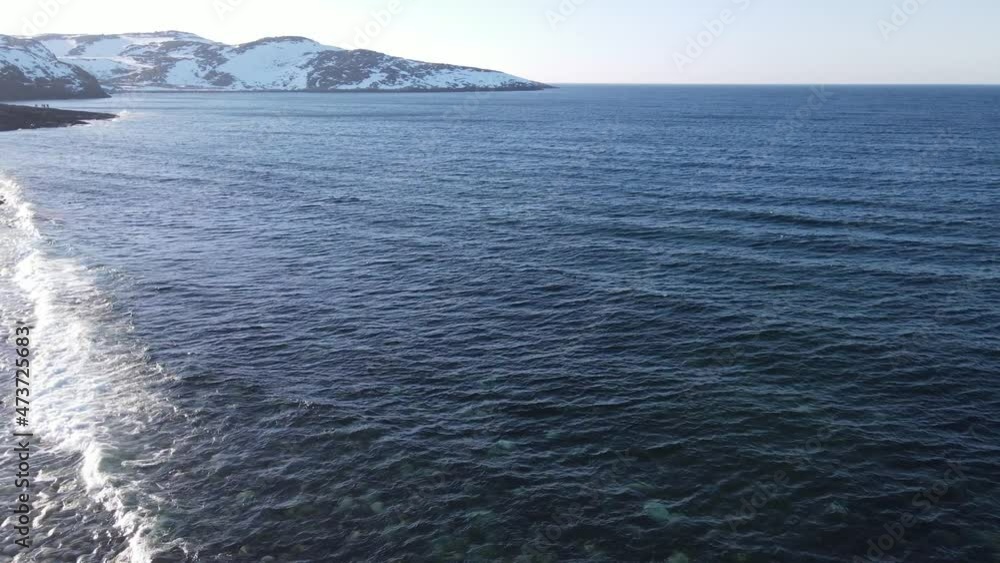 Winter aerial flight top over waves rolling on artic ocean shore with round stones, ocean waves at storm, 4k high quality drone video at winter Winter aerial flight top over waves rolling on artic ocean shore with round stones, ocean waves at storm, 4k high quality drone video at winter