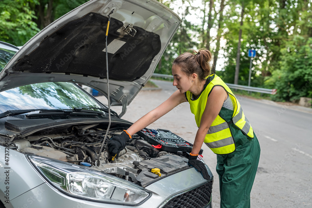 female mechanic in uniform trying to repair auto which broke down female mechanic in uniform trying to repair auto which broke down