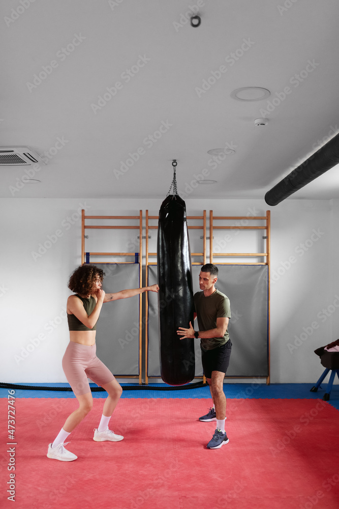 Woman Punching Boxing Bag with Trainer Woman Punching Boxing Bag with Trainer
