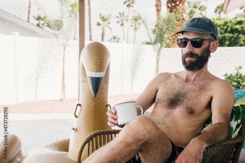 Shirtless man having coffee while relaxing at patio