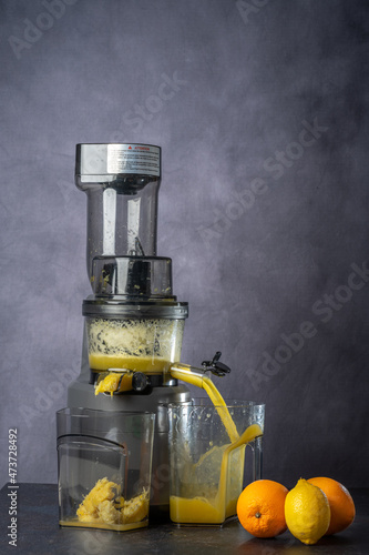 produce juice from oranges and lemons with a juice extractor. everything is photographed on a grey background