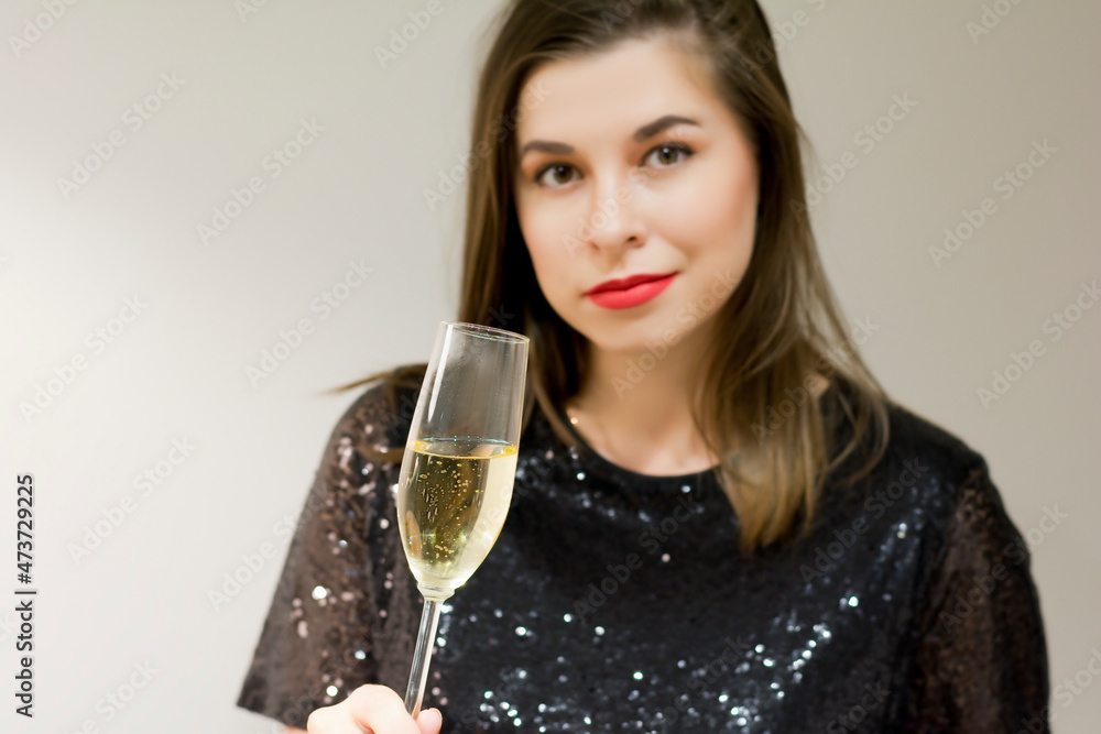 Beautiful woman in black dress with champagne glass of sparkling wine gray isolated copy space Beautiful woman in black dress with champagne glass of sparkling wine gray isolated copy space