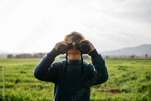 Smiling boy with binoculars in field photo