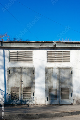 Fototapeta Naklejka Na Ścianę i Meble -  2 old rusted metal doors in the white concrete wall of electric transformer building