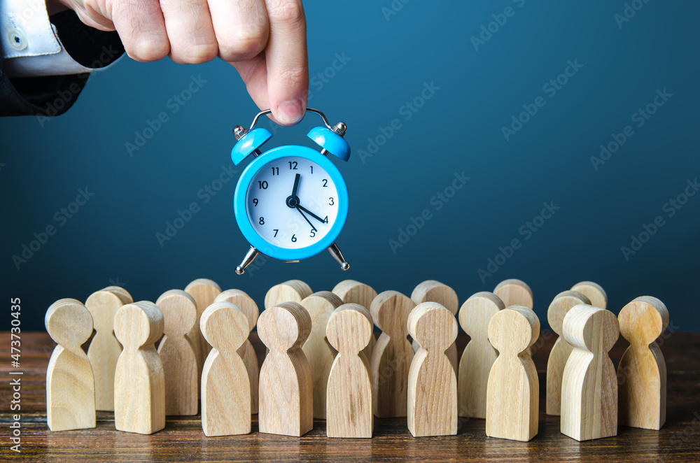 A businessman is holding an alarm clock over a crowd of people. Time management. Hourly wages, strict work limits and time allotted for rest. Urgently, speeding up, deadline. Test, trial period - obrazy, fototapety, plakaty 