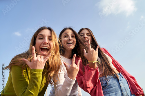Happy female friends gesturing horn sign while enjoying together photo