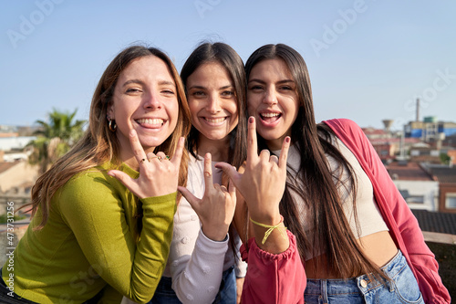 Female friends with cool attitude gesturing horn sign photo