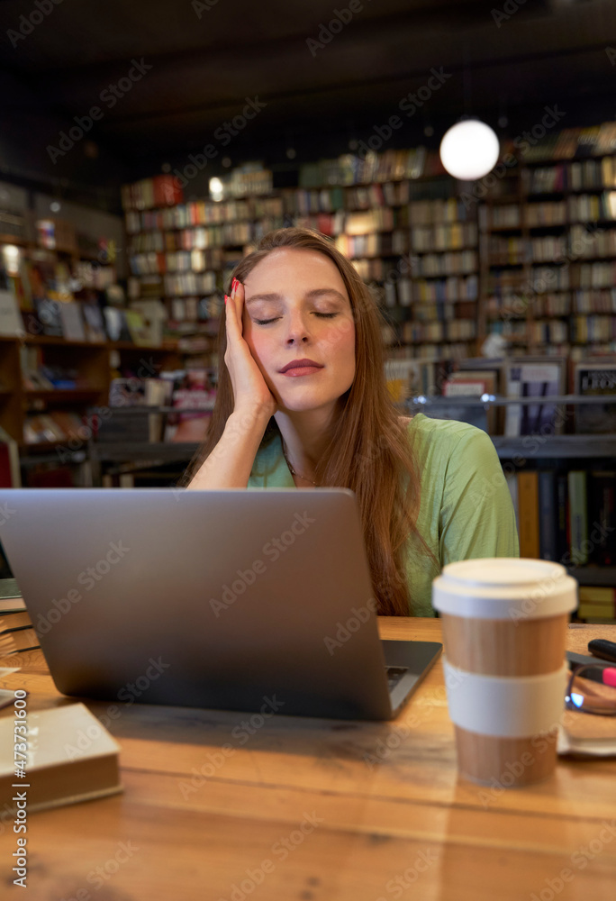 Young woman with eyes closed sitting in library Young woman with eyes closed sitting in library