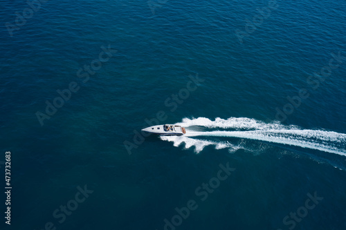 Boat performance U-turn on the water aerial view. Speedboat moving fast on dark blue water.