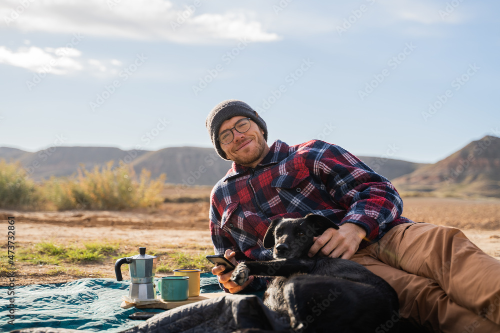 Man and dog having coffe in the middle of desert Man and dog having coffe in the middle of desert