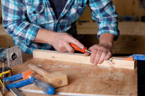  A carpenter in a plaid shirt works a workshop. Wood. Ecological compatibility. Lifestyle. Close up.