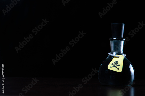 vial of poison with a hazard warning label, on a dark background, toning, short focus