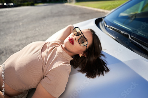Relaxed woman lying on car hood photo