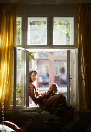 Woman Using A Phone While Sitting At The Window photo