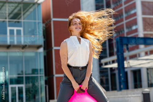 Smiling businesswoman enjoying on bouncy ball during sunny day