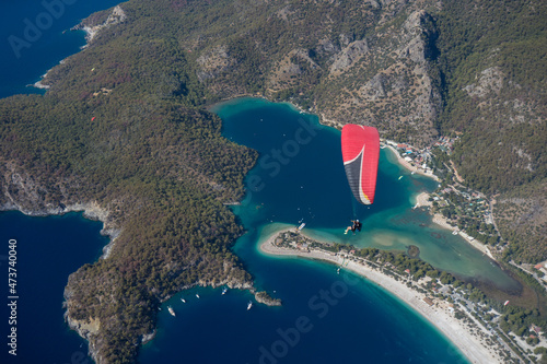 paraglider flying above scenic coastline of oludeniz