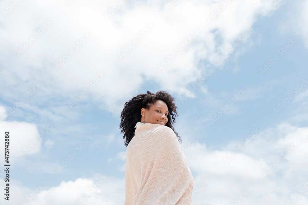 Smiling woman wrapped in towel on sunny day