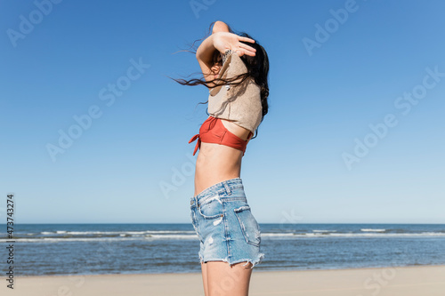 Young woman removing clothes at beach
