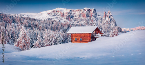 Panoramic morning view of Alpe di Siusi village with wooden chalet. Wonderful winter sunrise in Dolomite Alps with Santner and Euringer peaks on background. Perfect landscape of ski resort, Ityaly. photo