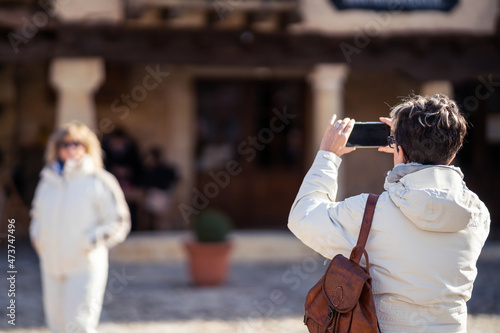mujer joven y atractiva posando, mirando y haciendo fotos con el movil en un pueblo de la sierra de Segovia