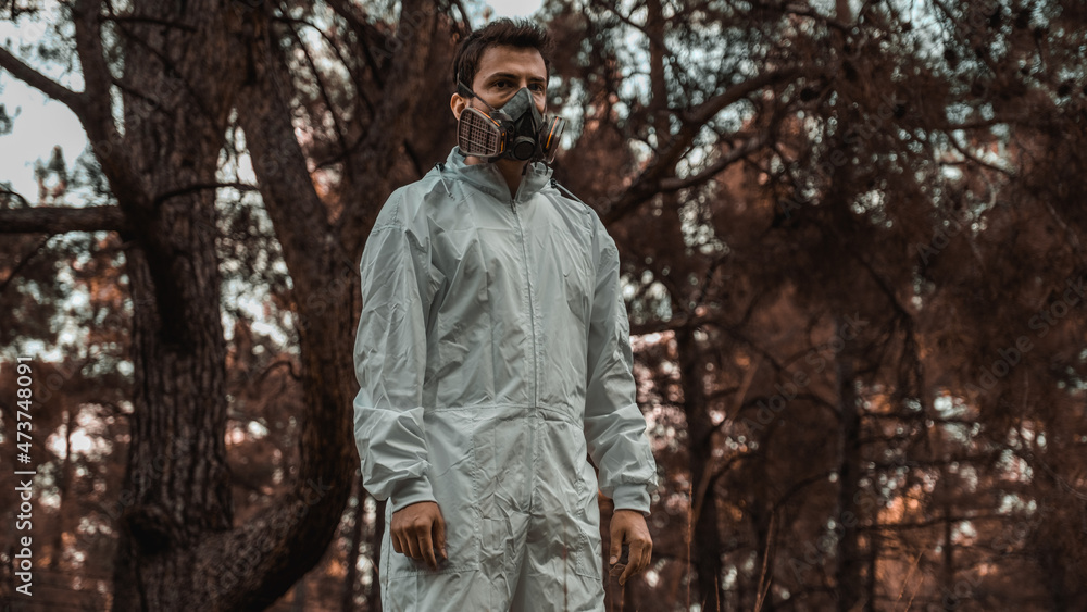 Man in white overalls wearing a gas mask in a post apocalyptic nature