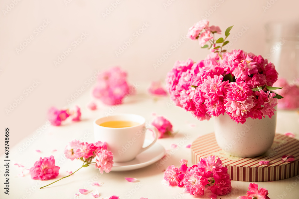 roses and tea cup served for breakfast on plain background, copy space for text, valentine's day, wedding or anniversary morning decorations. roses and tea cup served for breakfast on plain background, copy space for text, valentine's day, wedding or anniversary morning decorations.