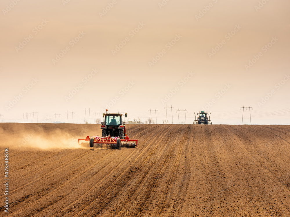 Obraz premium Tractor at agricultural farm field cultivating land