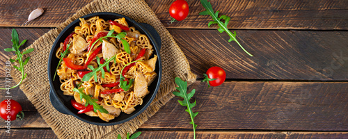 Tasty pasta in tomato sauce with chicken, pepper and herbs on wooden background. Top view